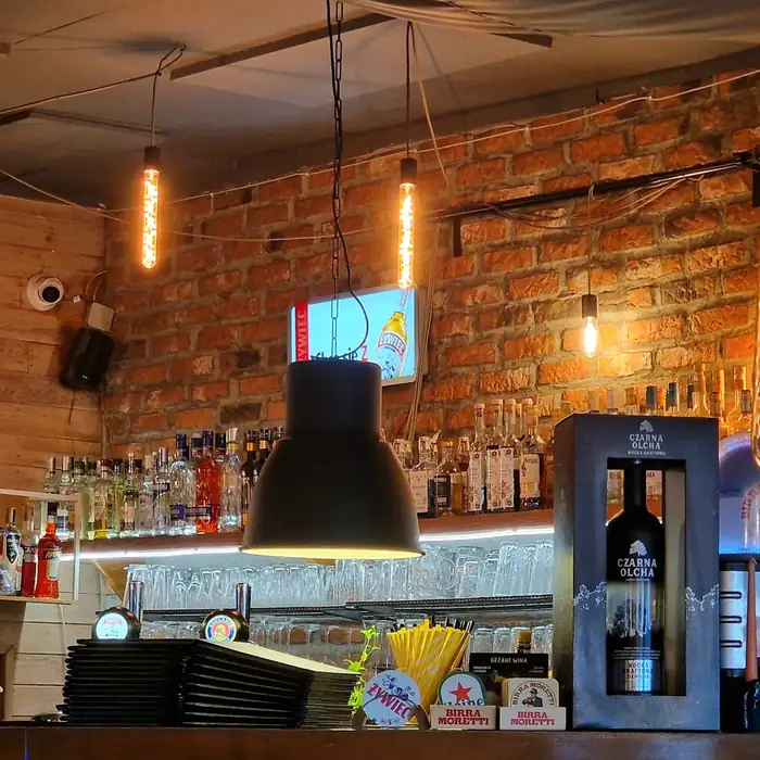 Bar z cegły z czarnymi lampami i podświetlonymi butelkami